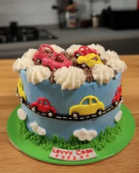 Boy cake with blue sky buttercream and fondant race cars on a cake stand