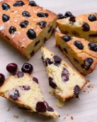 Rustic cherry cake with golden crust and fresh cherries on a cooling rack