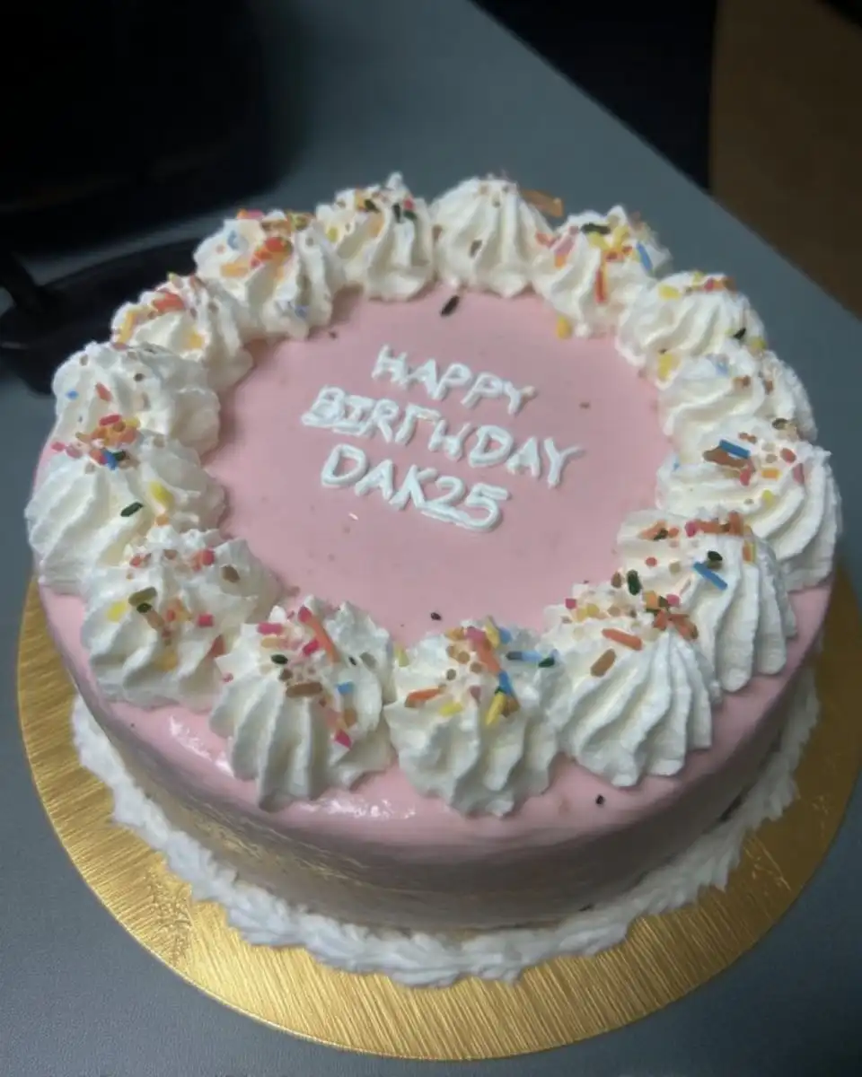 A 4 inch minimal cake with white frosting and rainbow sprinkles