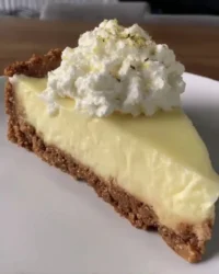Slice of creamy lemon cheesecake with lemon curd topping on a white plate