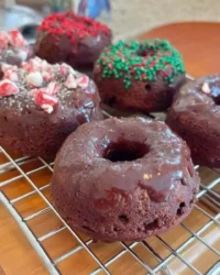 Slice of peppermint chocolate cake with ganache drip and candy cane sprinkles on a festive plate