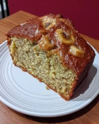 Rustic banana cake with cream cheese frosting on a cooling rack