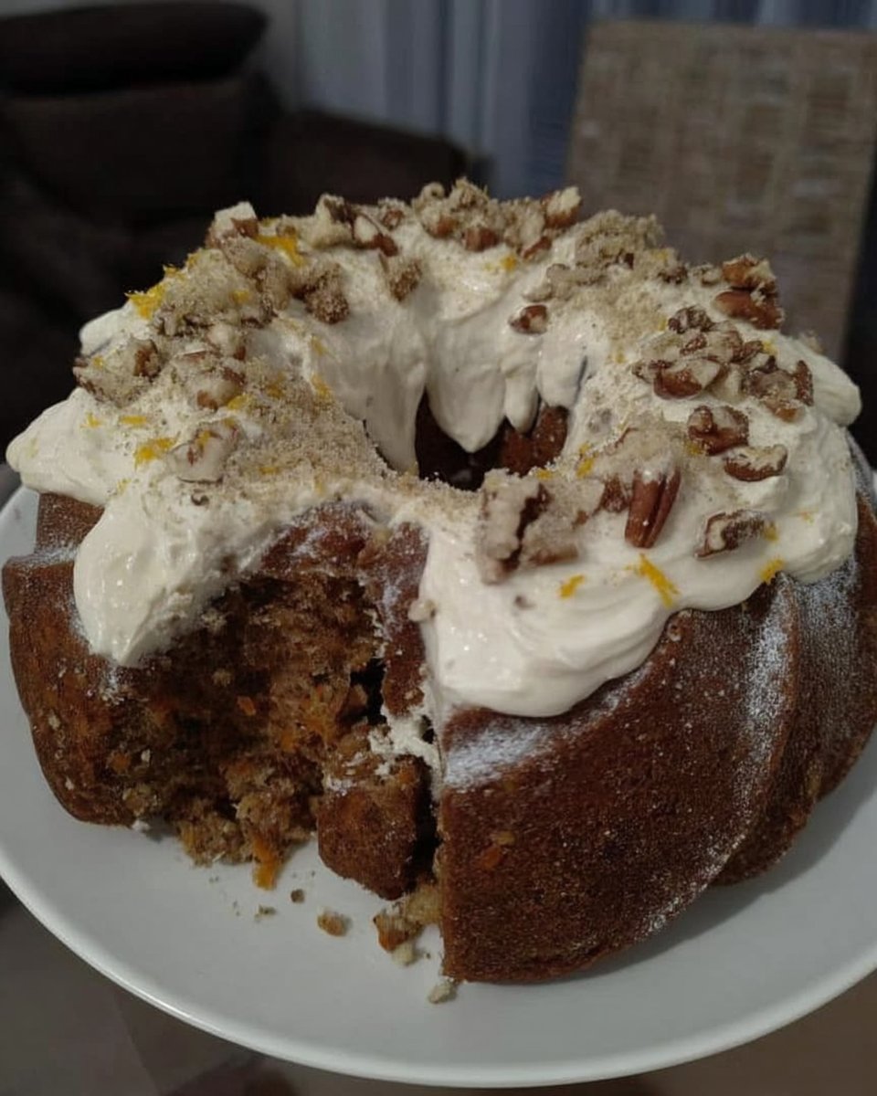 Rustic carrot cake on a wooden table with fresh carrots nearby