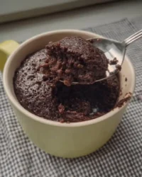 Warm chocolate mug cake sitting on a rustic wooden table
