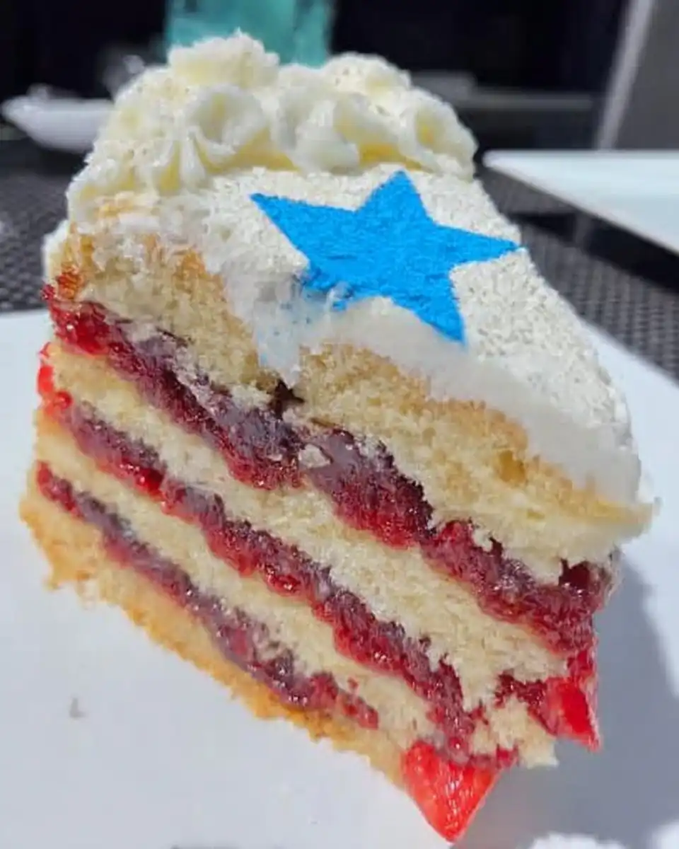 Slice of red white and blue cake on a white plate with a fork