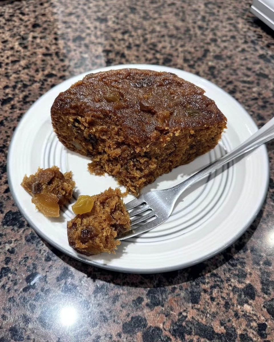 Thin slice of fruitcake on a plate with a mug of coffee