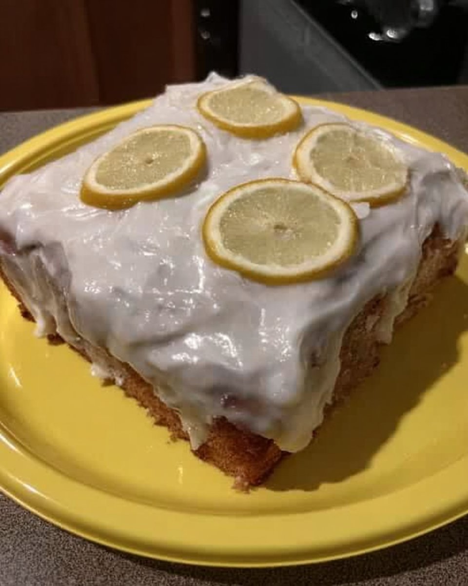 Slice of moist lemon cake on a white plate with a fork
