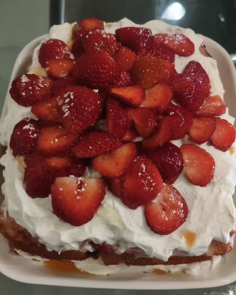 Slice of strawberry poke cake showing red gelatin streaks and whipped topping