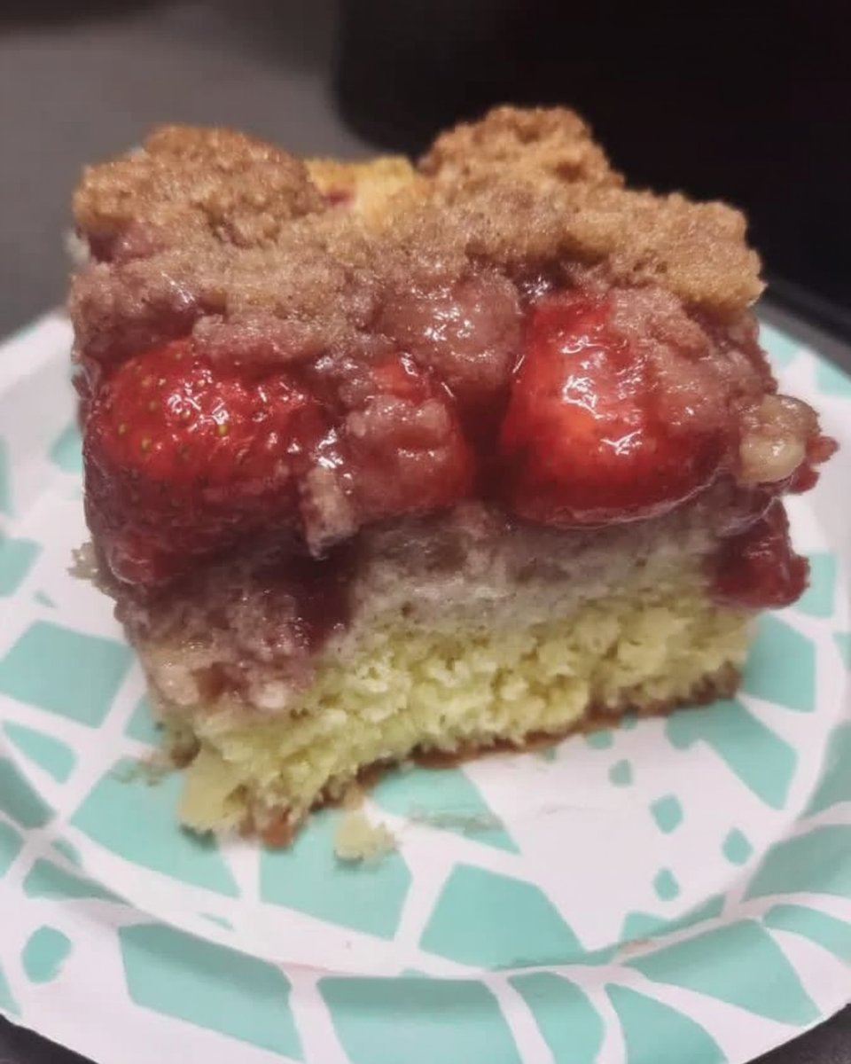Slice of moist strawberry rhubarb cake with a golden top on a white plate