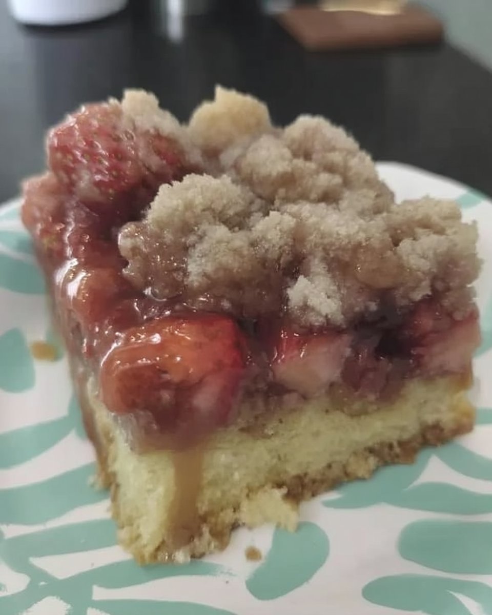 Square of strawberry rhubarb cake served with a cup of coffee