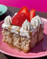 Slice of pink strawberry tres leches cake with whipped cream and freeze dried strawberries