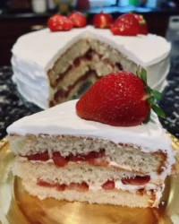 Slice of strawberry vanilla cake with pink buttercream on a white plate