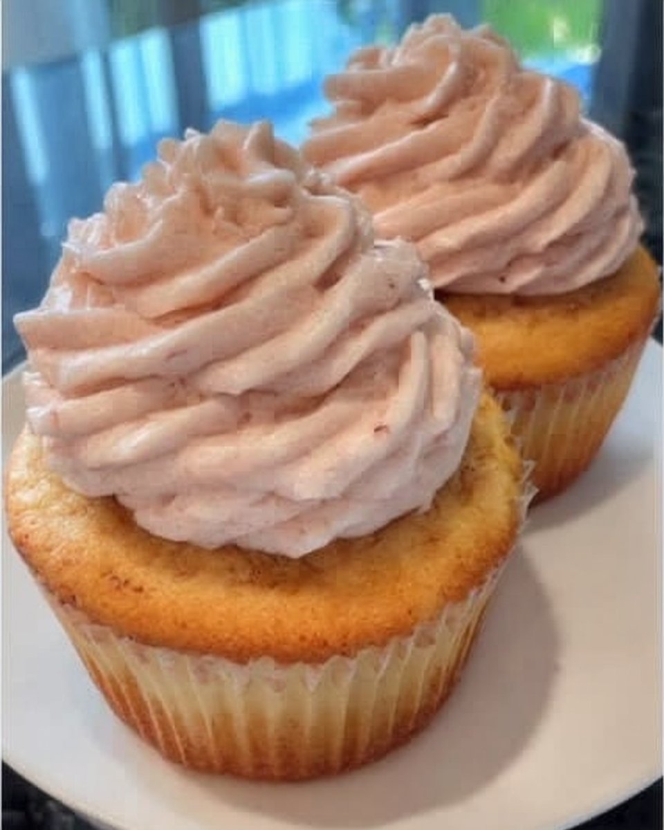 Whole frosted pink champagne cake on a glass cake stand