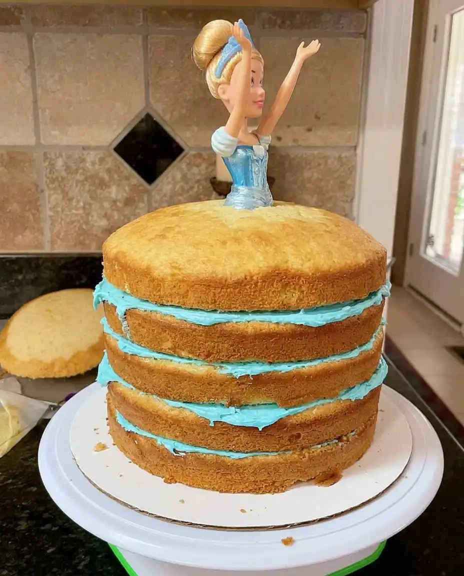 A serrated knife carving a tall stacked cake into a rounded skirt shape