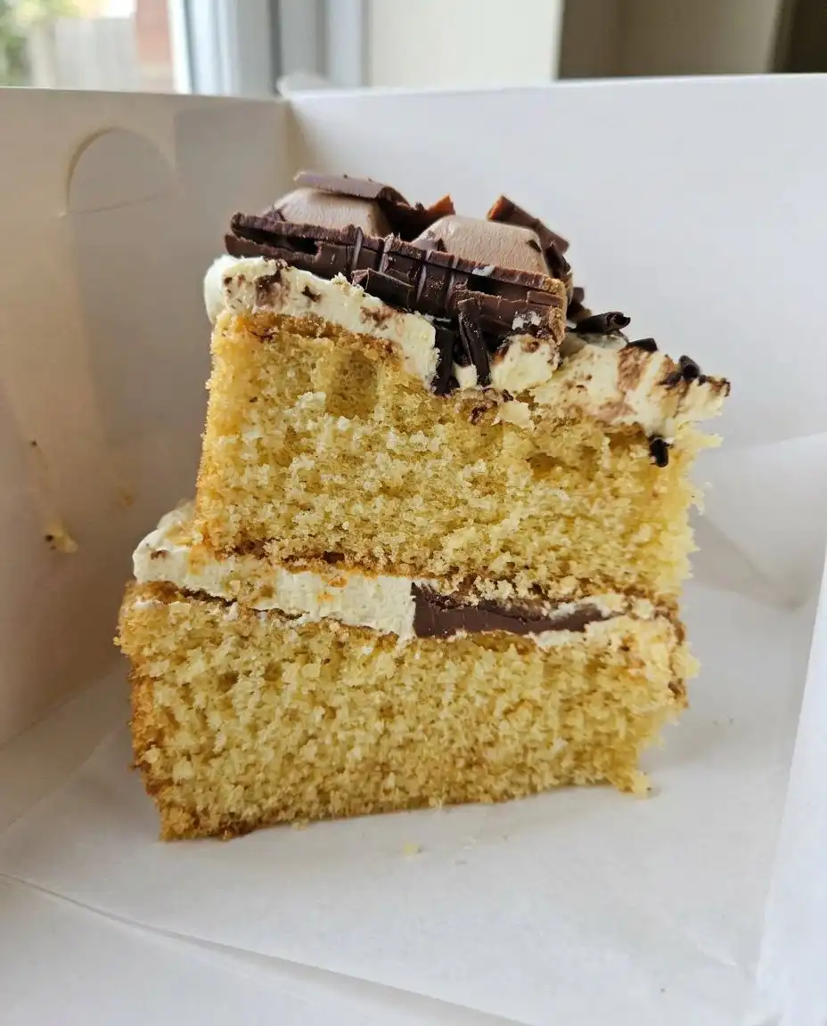 A hand inserting a wooden skewer into a rectangular cake in a baking dish.