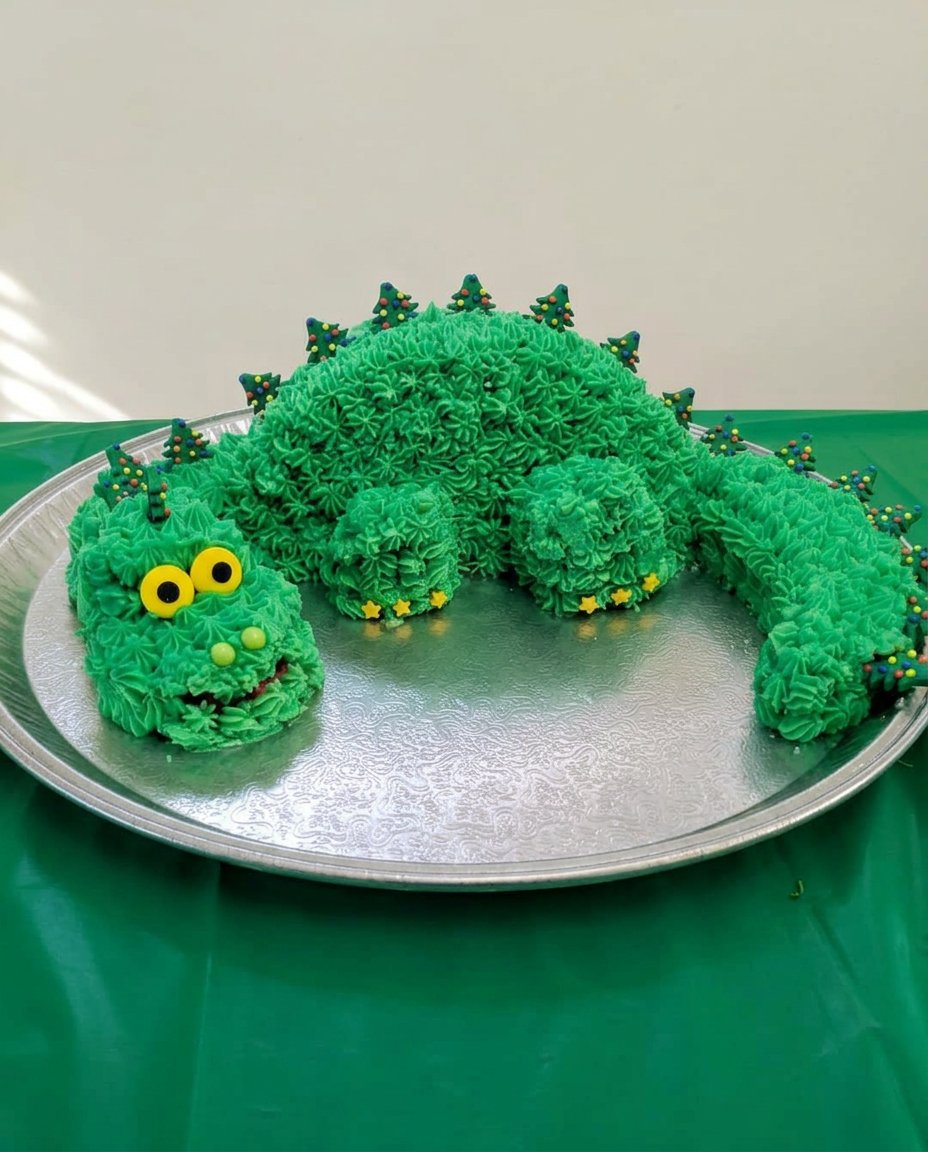 A slice of chocolate dino cake with turquoise icing on a white plate.