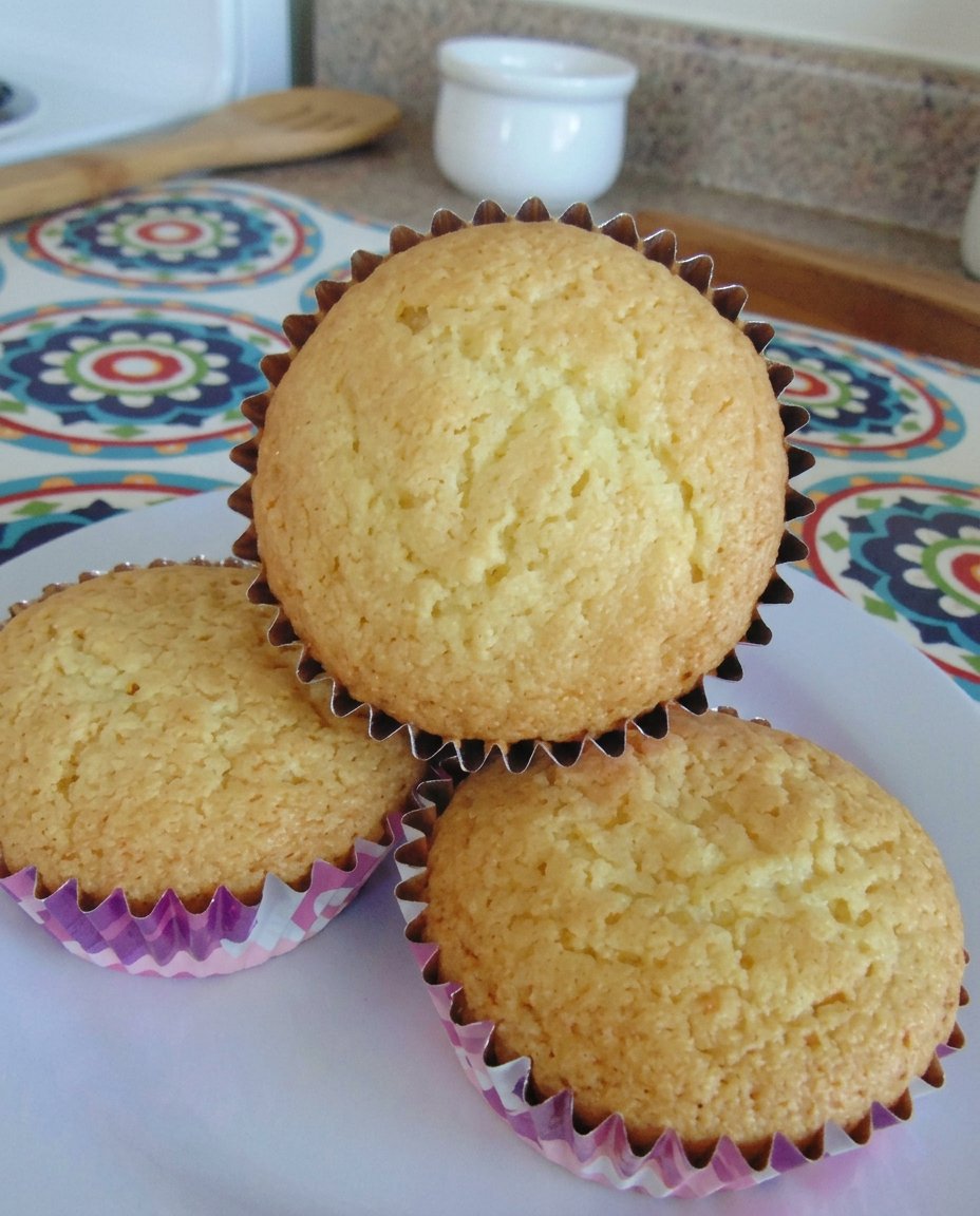 A dozen golden fairy cakes sitting on a rustic wooden tray