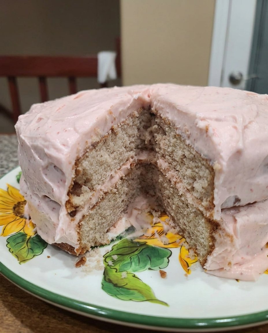 A flat lay of cake ingredients including flour, butter, sugar, and a bowl of bright red strawberries