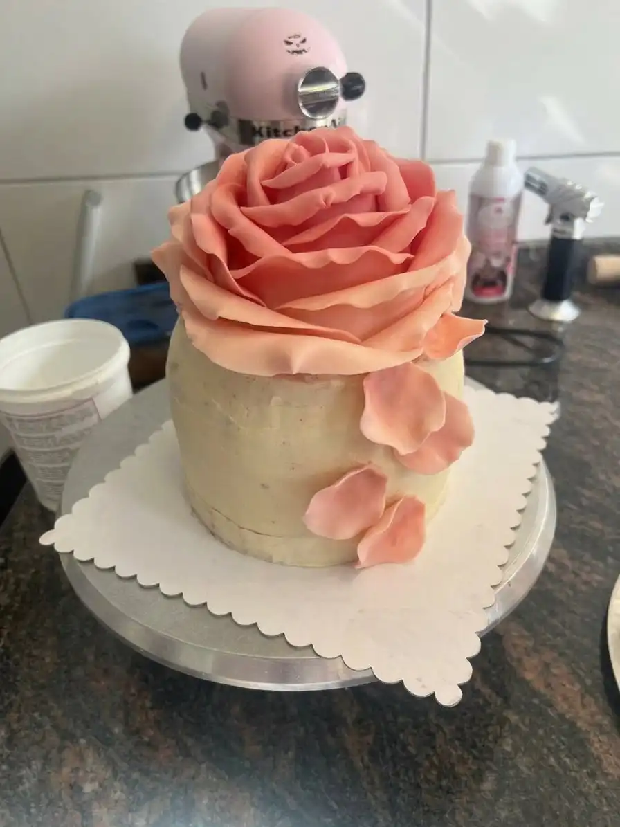 Baking ingredients including cake flour, rose water, butter, and fresh roses on a marble surface.