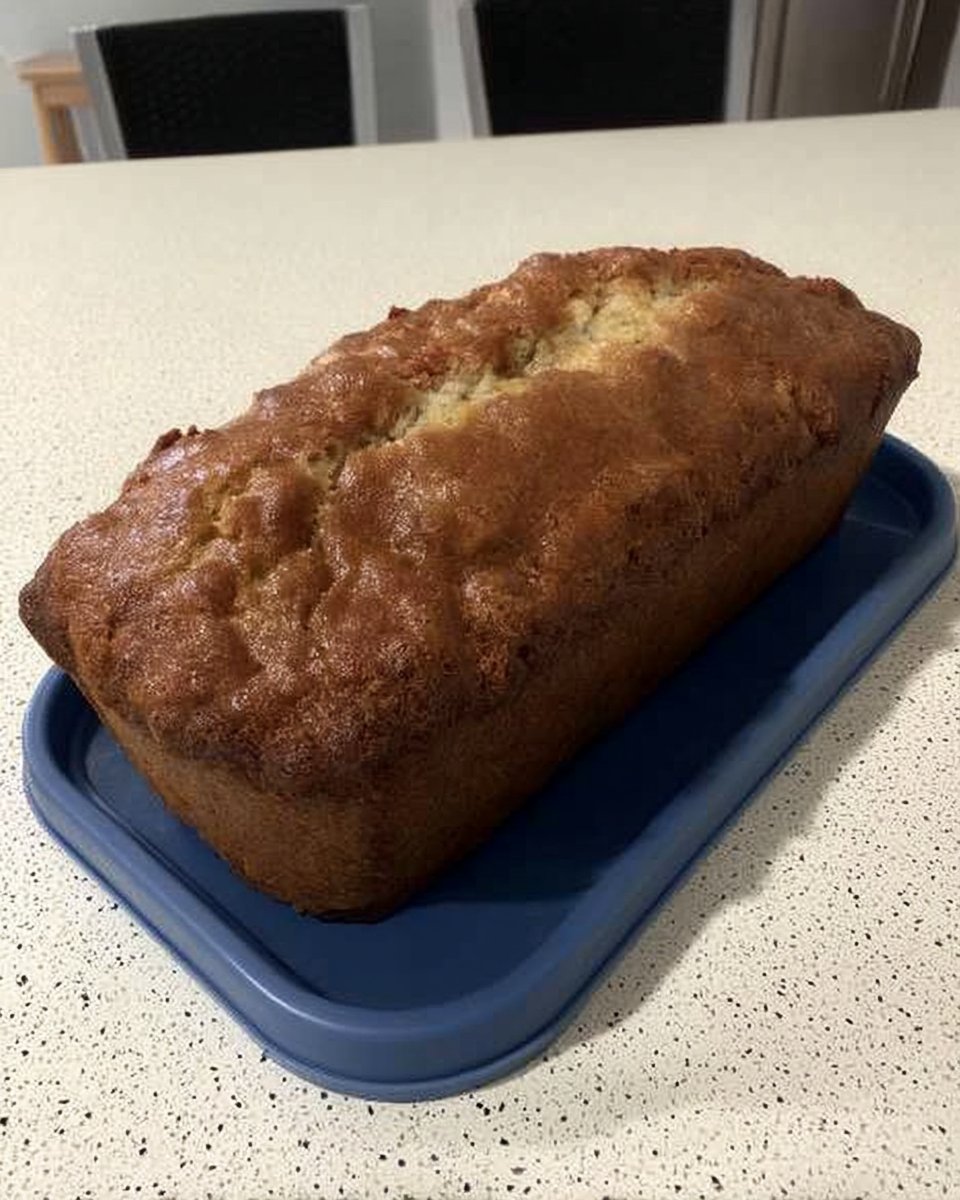 A close-up shot of the lemon glaze being poured over the top of a golden cake.