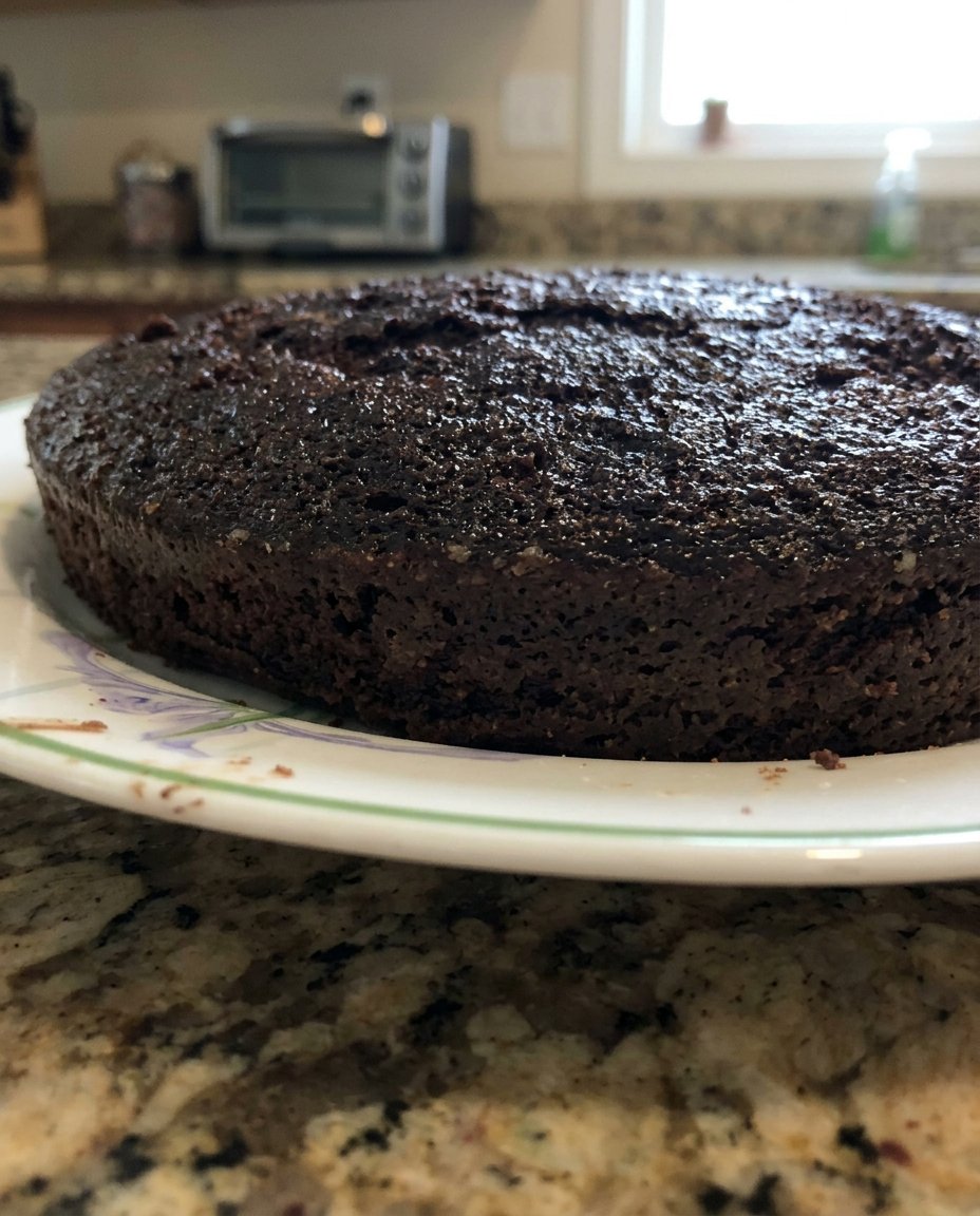 A close up of a moist vegan chocolate cake slice with a tender crumb and rich frosting.