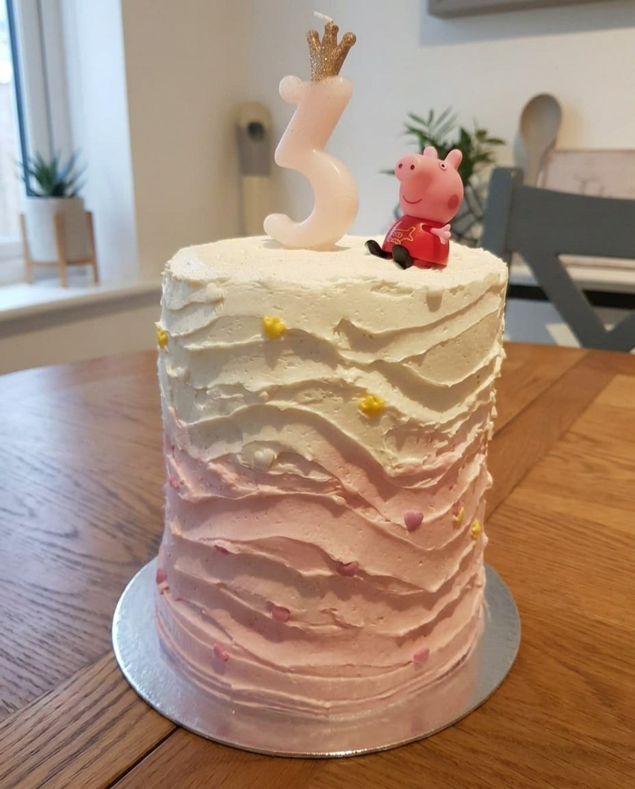 Close up of piping pink buttercream rosettes onto a cake