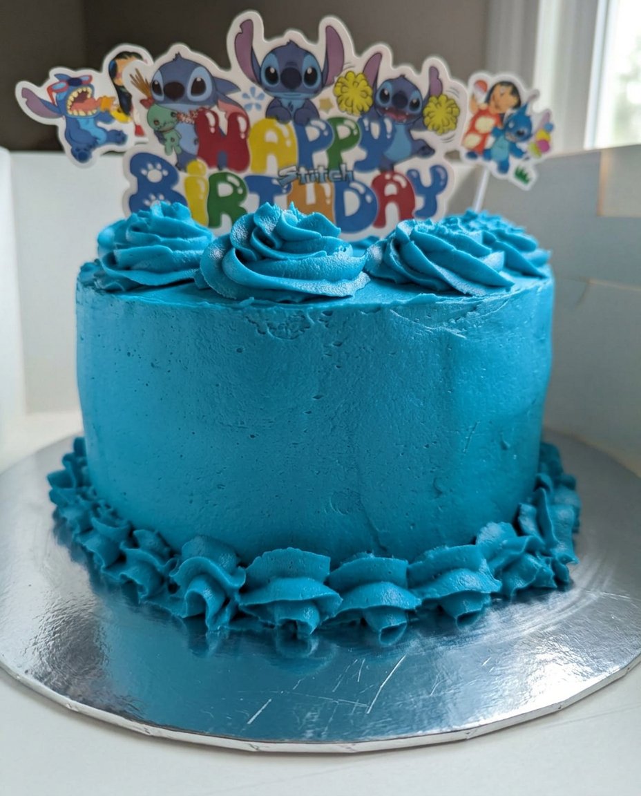 A rustic chocolate layer cake topped with silky buttercream and fresh cherries on a wooden table.