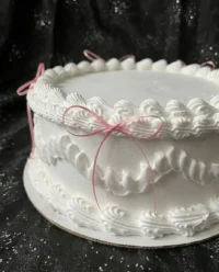 A vintage coquette cake with pink buttercream ruffles and a heart shape