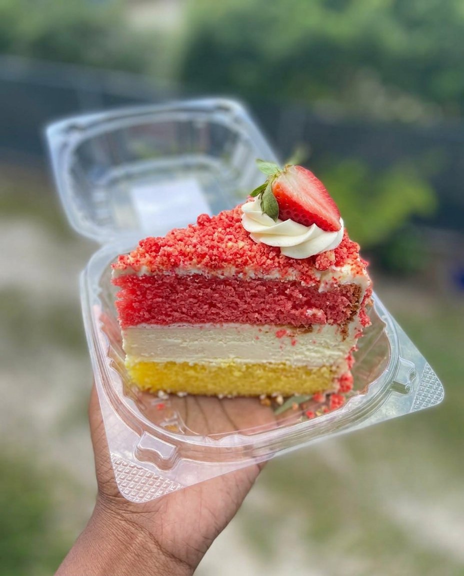 A square of carrot cake slice on a ceramic plate next to a cup of tea.