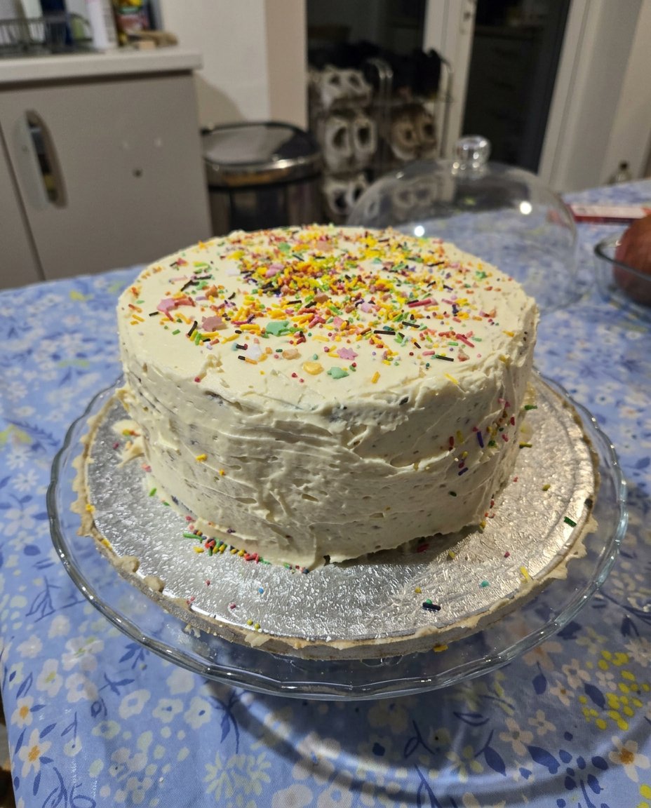 A single slice of birthday cake with chocolate frosting on a wooden serving board
