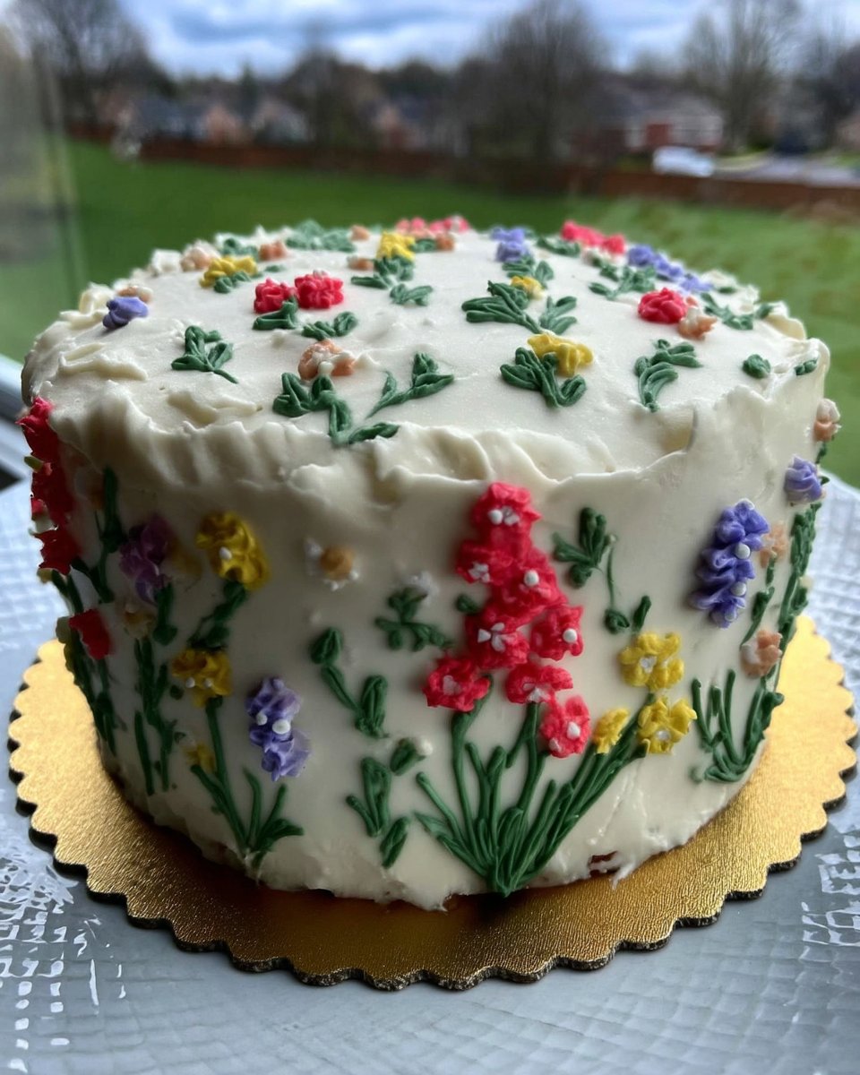 A three tiered spring cake decorated with colorful buttercream flowers and birch bark texture