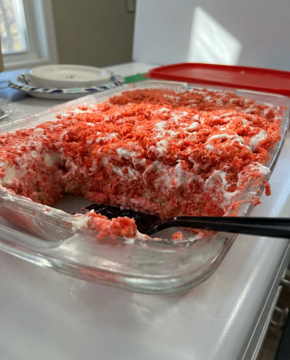 A moist slice of strawberry crunch cake with whipped frosting and pink cookie crumbles