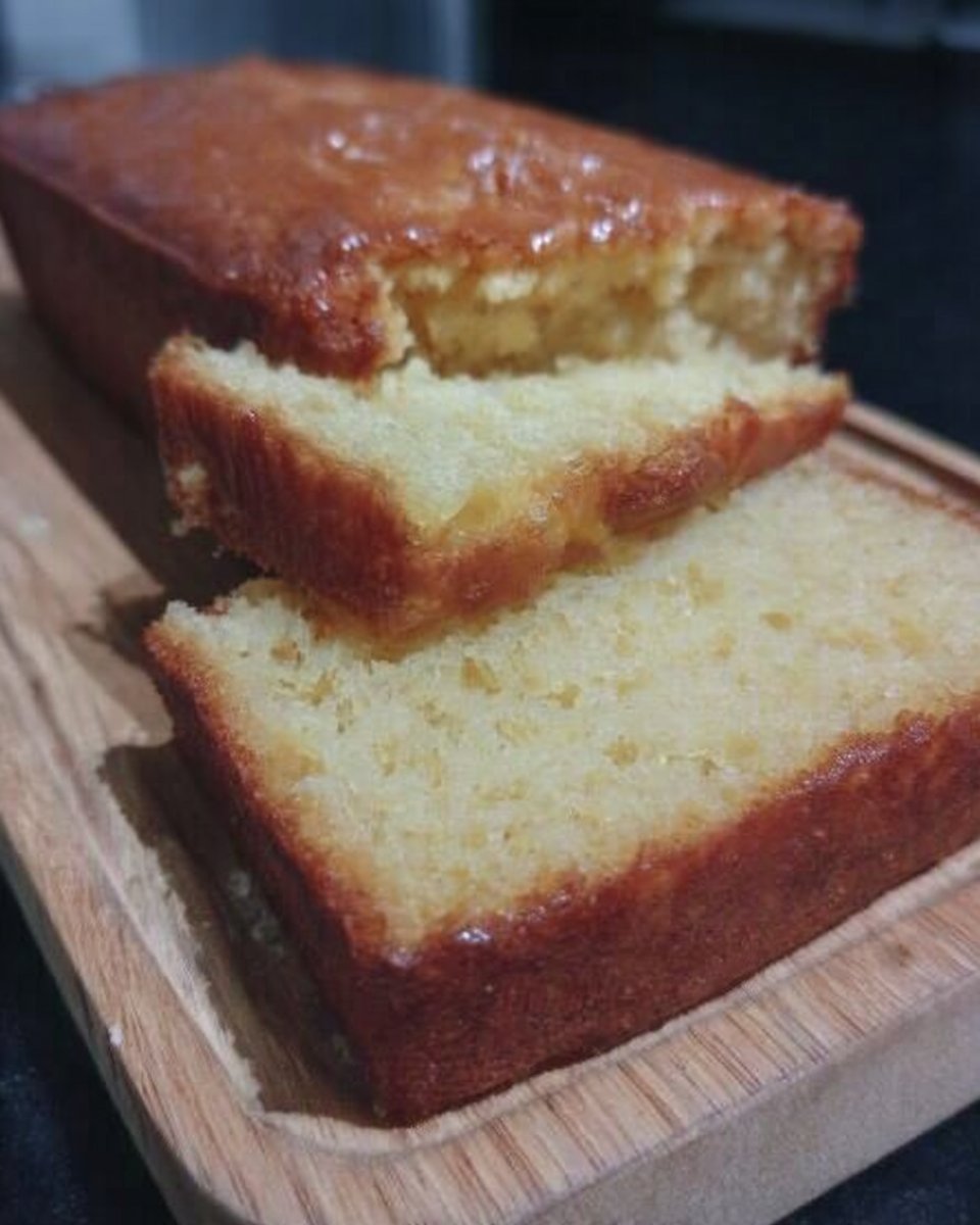 A golden round lemon yogurt cake resting on a wire cooling rack with a bright white glaze dripping down the sides.