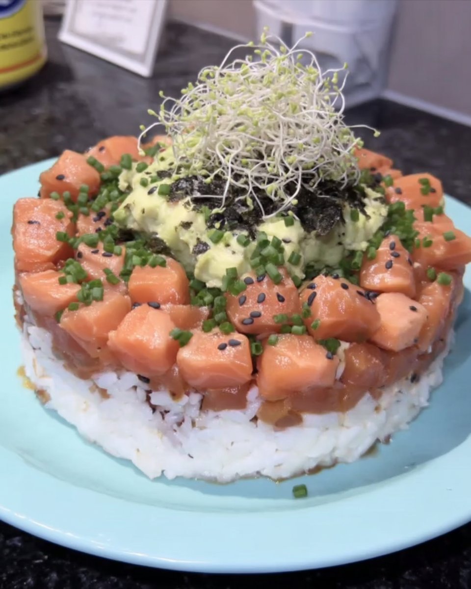 Sushi Cake 14 A completed sushi cake on a dark ceramic platter with sesame seeds