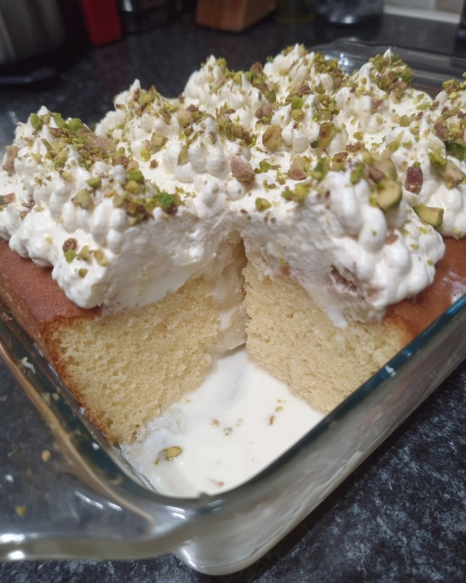 A perfectly soaked slice of Tres Leches cake with whipped cream and cinnamon