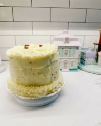 Layering ready-made sponges and strawberry frosting for a fake cake base