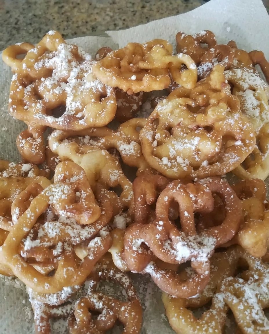 Ingredients for funnel cake including flour sugar milk and eggs arranged on a marble surface.