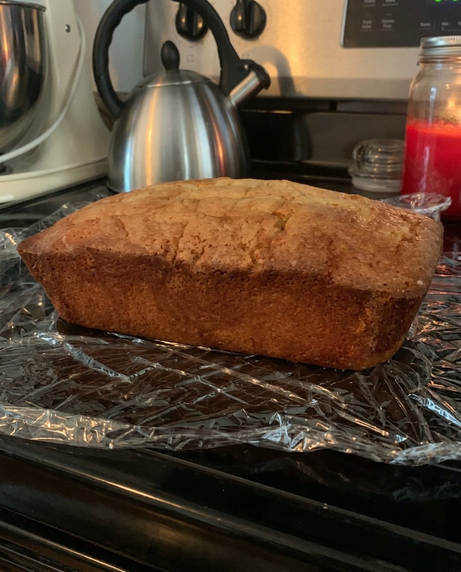 Lemon Drizzle Cake 3 13 A hand using a wooden skewer to poke holes into the top of a warm golden loaf cake.