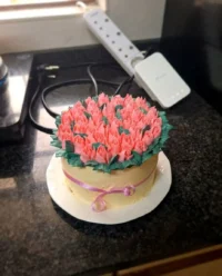 A rustic tulip cake with hand-piped buttercream flowers on a wooden table
