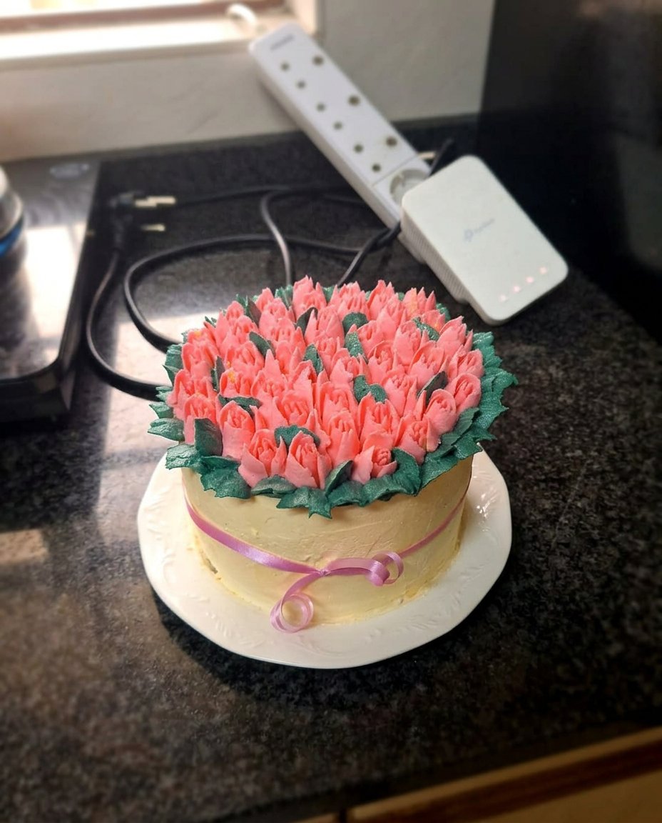A rustic tulip cake with hand-piped buttercream flowers on a wooden table