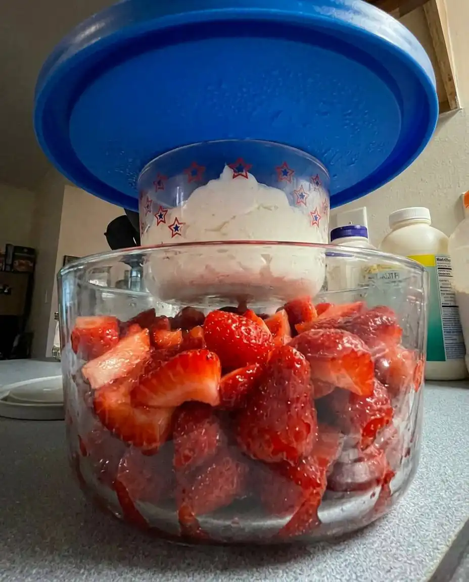 A variety of fresh strawberries, blueberries, and raspberries next to a bowl of almond stabilized cream.