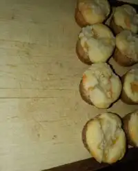 Golden canned peach cobbler muffins cooling on a wire rack with visible streusel topping.