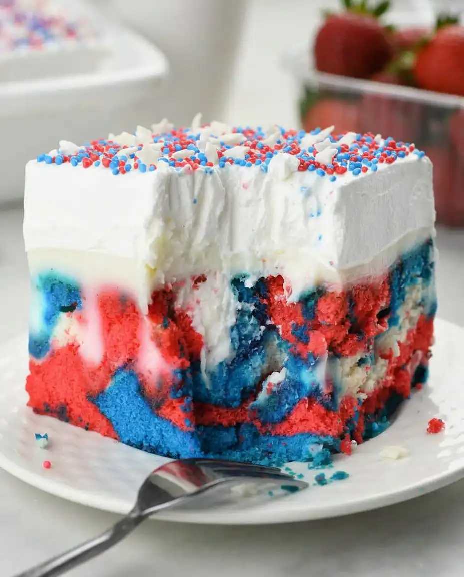 A fully decorated patriotic poke cake with whipped cream and sprinkles served at a cookout