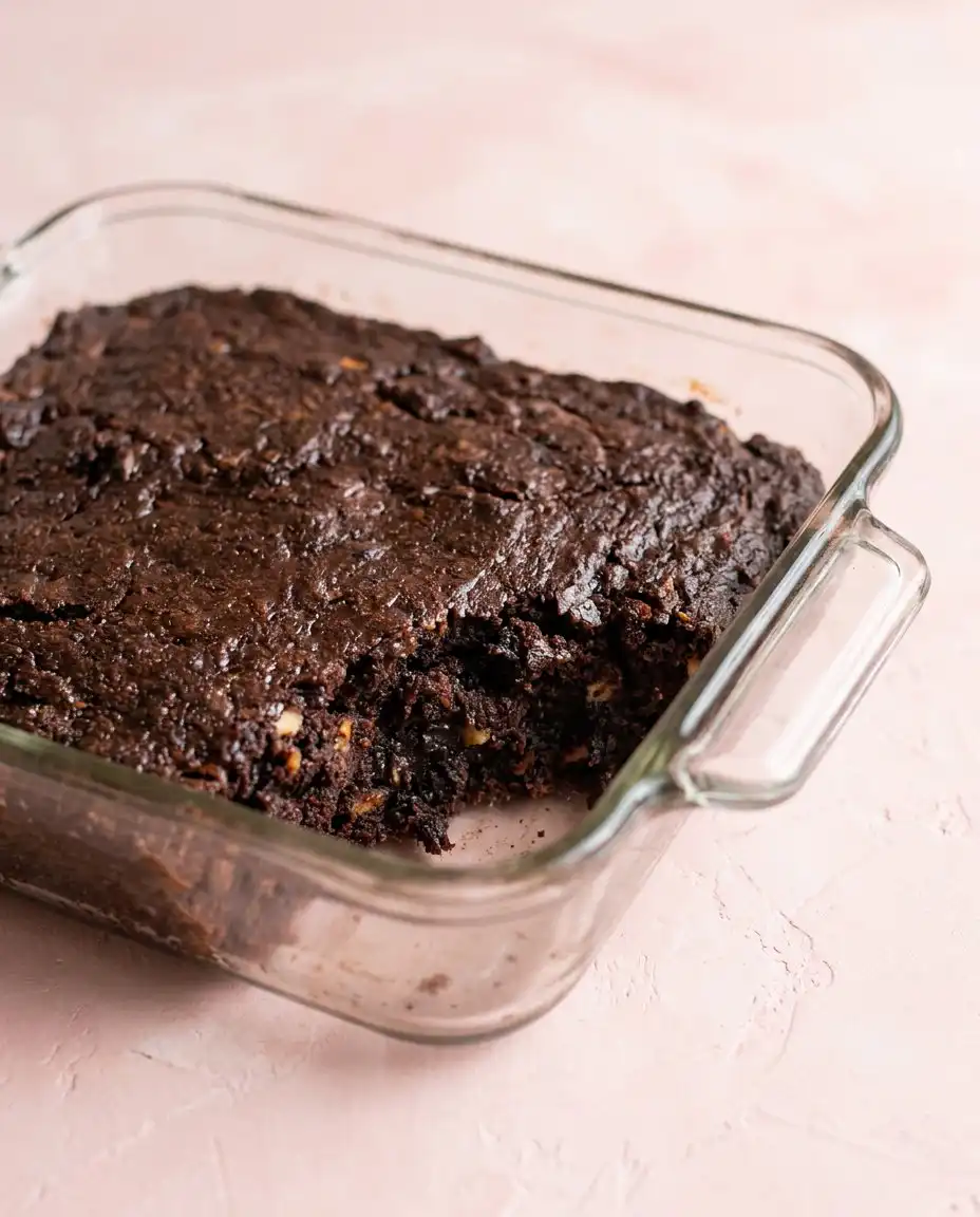 An Old-Fashioned Chocolate Zucchini Cake in a 9x13 pan cooling on a sunny farmhouse windowsill.