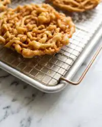 A golden Classic Carnival Funnel Cake dusted with powdered sugar on a plate.