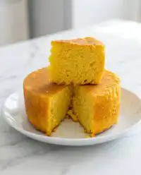 A close up view of the assembly process for a Classic Mango Sponge Cake with cream and mango slices.