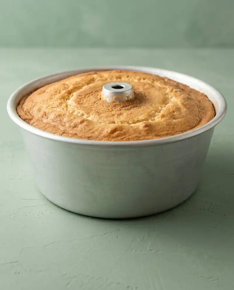 A golden Classic Peach Pound Cake resting on a rustic wooden cutting board in a farmhouse kitchen.