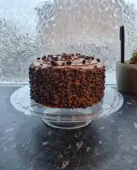 A six layer death by chocolate cake with glossy ganache on a vintage cake stand.