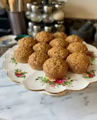 A close up shot of golden brown Banana Zucchini Muffins 2 resting on a professional wire cooling rack.