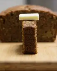 A golden brown loaf of apple zucchini bread cooling on a wire rack in a test kitchen.